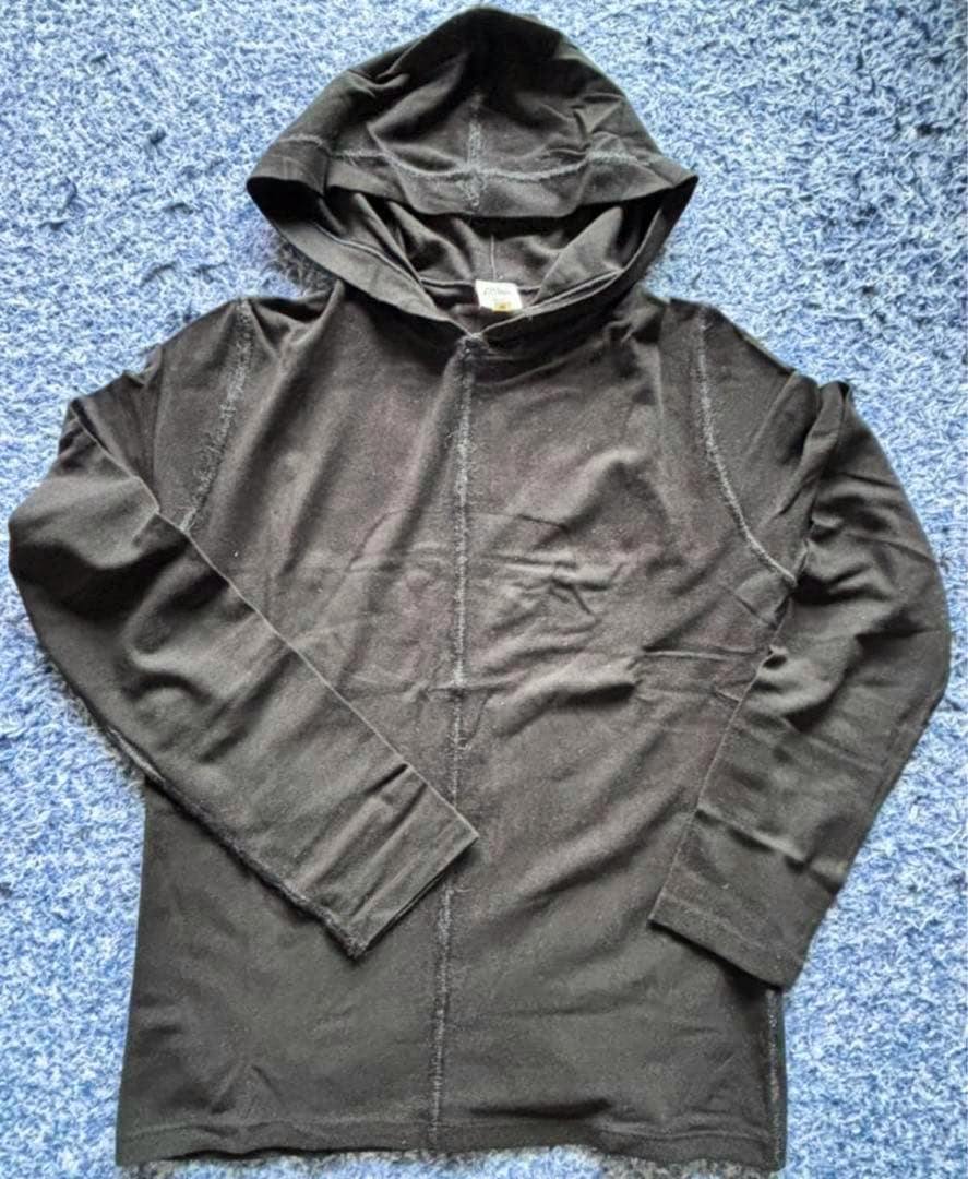 Black Jean Paul Gaultier HOMME hooded sweatshirt laid flat on a blue rug.