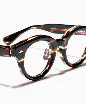 Close-up photo of tortoiseshell round eyeglasses resting on a white surface.