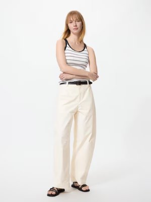 A model wearing light-colored barrel-leg pants standing full-length against a white background.