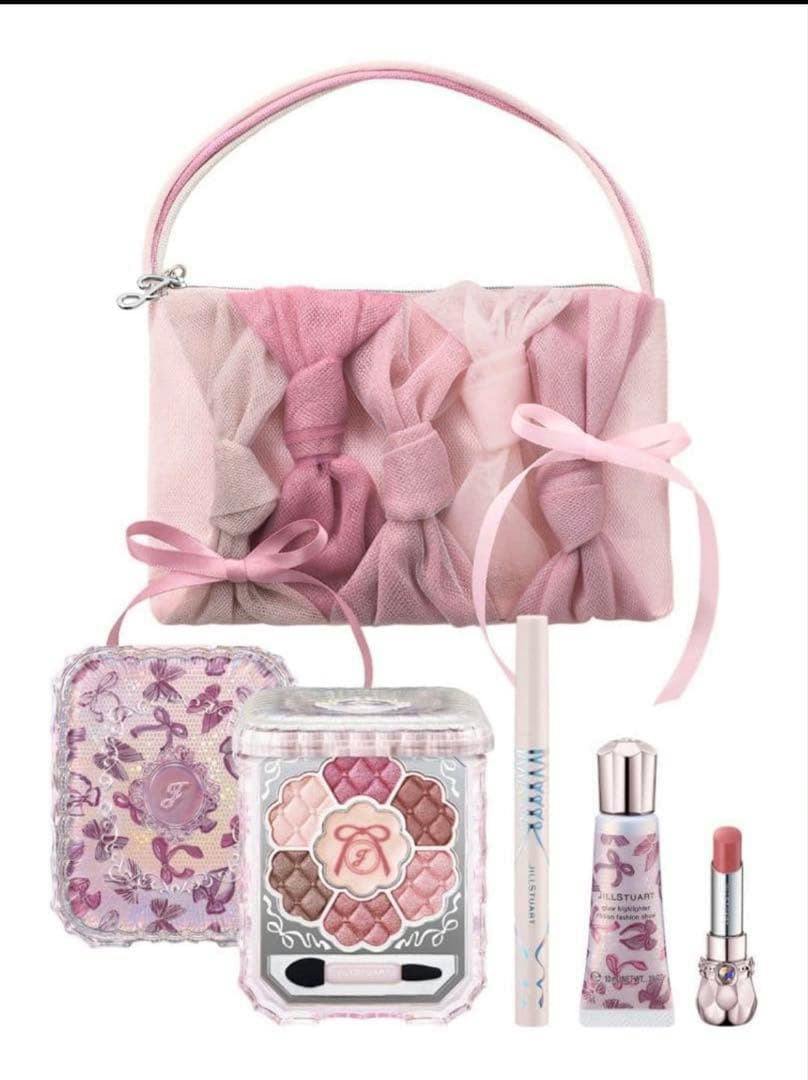 A pink bow-decorated makeup pouch with a Jill Stuart eyeshadow palette, eyeliner, lip product, and small cosmetic tube displayed.