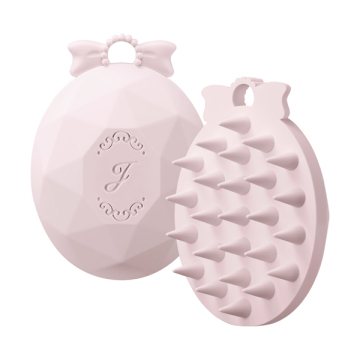 Pink Jill Stuart shampoo brush shown front and back with faceted oval body, bow loop, and silicone bristles.