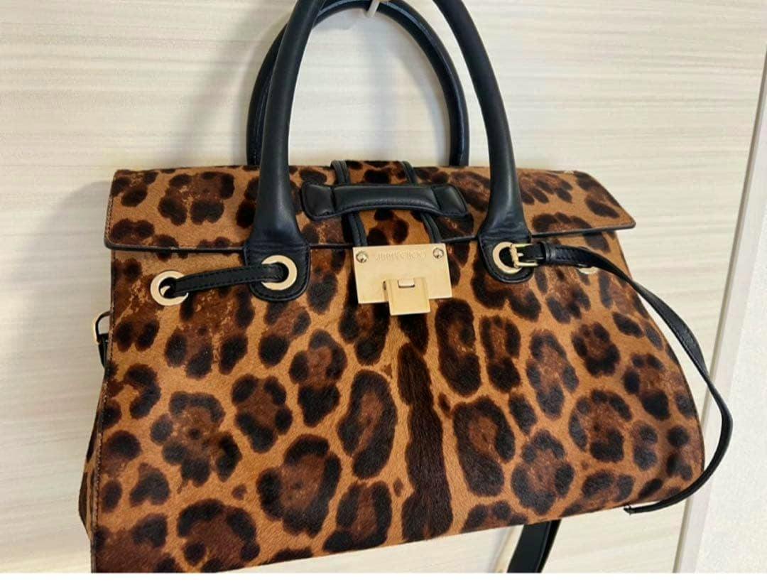 Leopard-print Jimmy Choo haircalf shoulder handbag with black handles and a gold clasp shown against a light background.