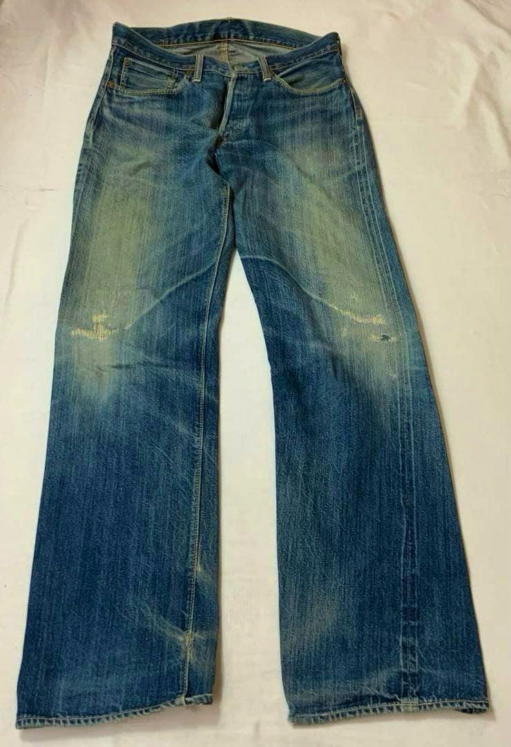 Front view of the men's denim jeans laid flat on a light background showing faded wash and wear marks.