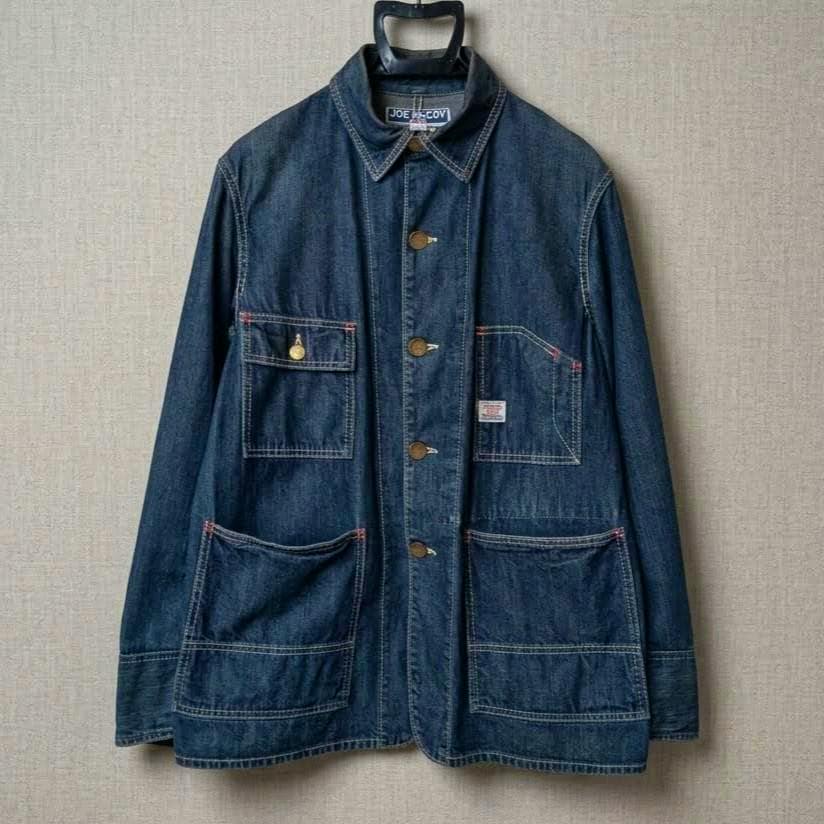 Front view of a JOE McCOY denim coverall jacket (size 38) hanging on a hanger against a neutral background.
