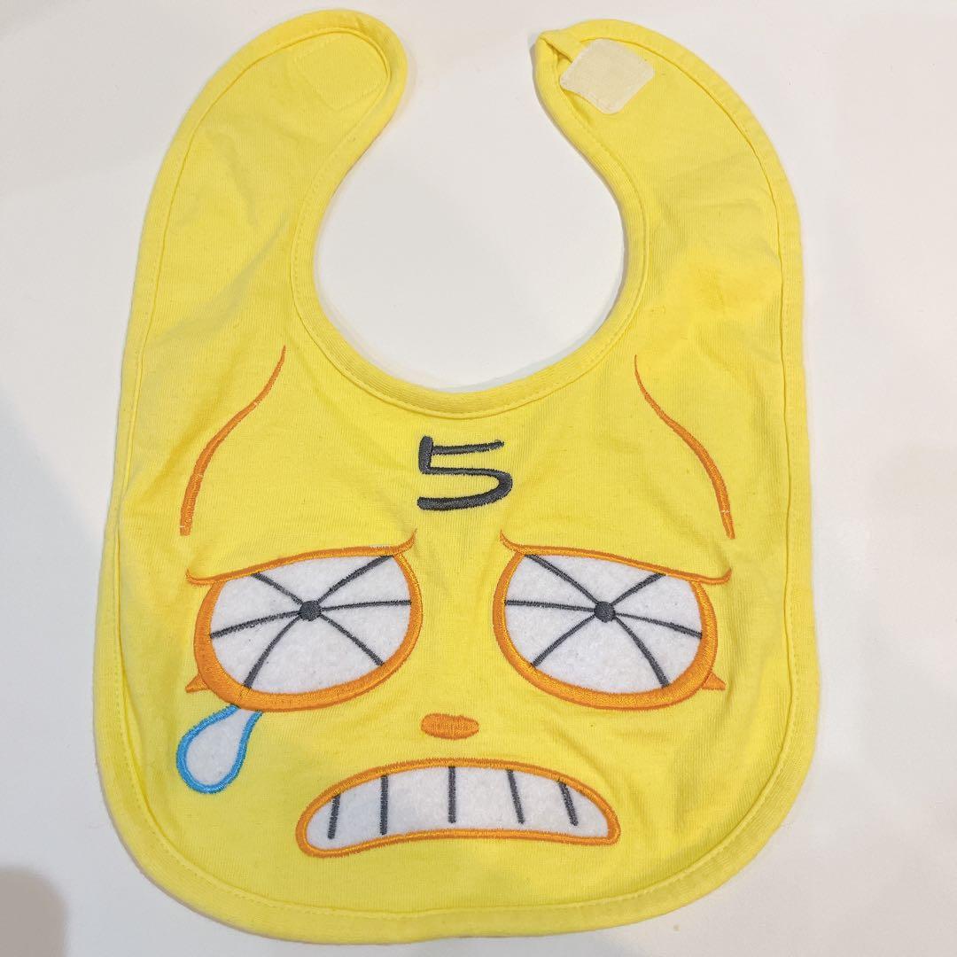 Yellow cotton baby bib with a stylized crying face design and the number 5 at the top.