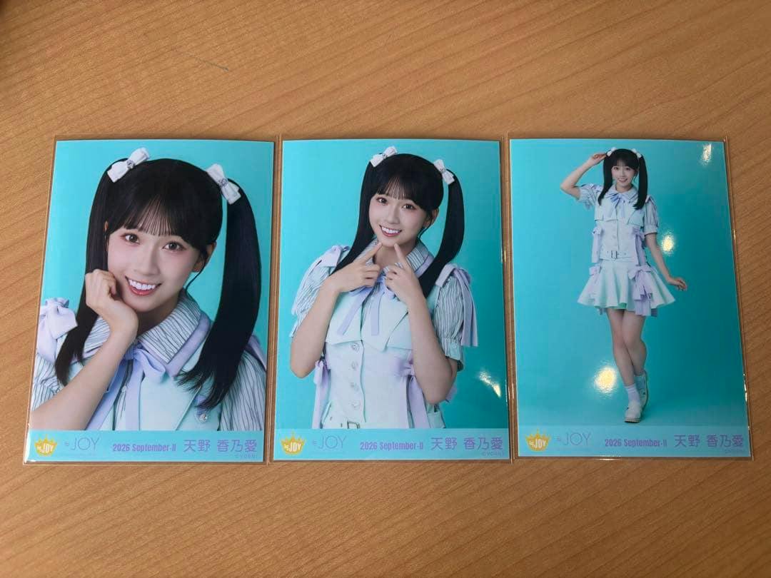 Three printed photocard images from the set show the subject wearing a summer twin-tail singing costume against a turquoise background, arranged side-by-side on a wooden surface.