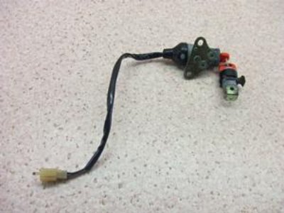 A motorbike key switch assembly with wiring and plastic connector laid on a light speckled surface.