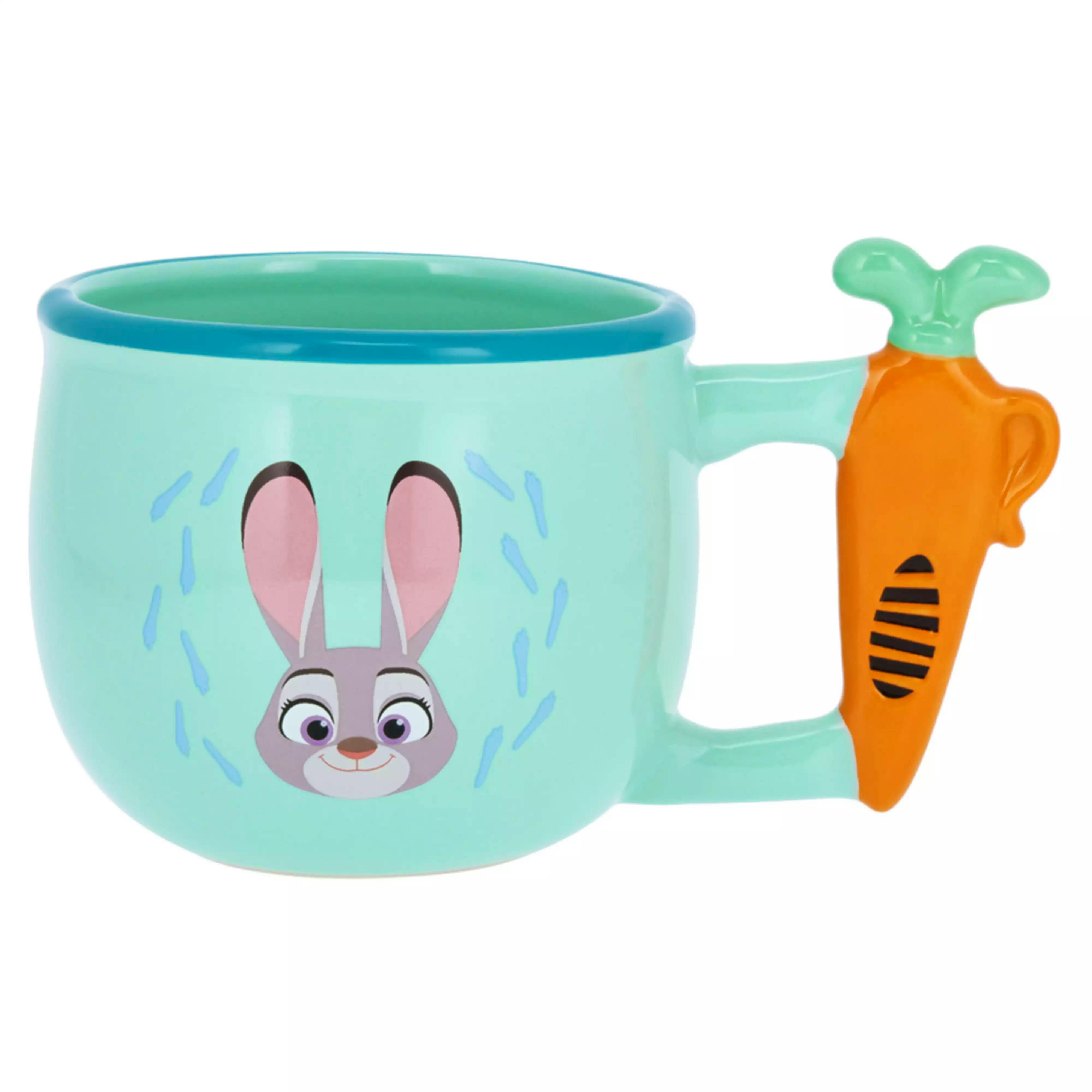 Close-up of a light turquoise ceramic mug showing a rabbit face print and an orange carrot-shaped handle.