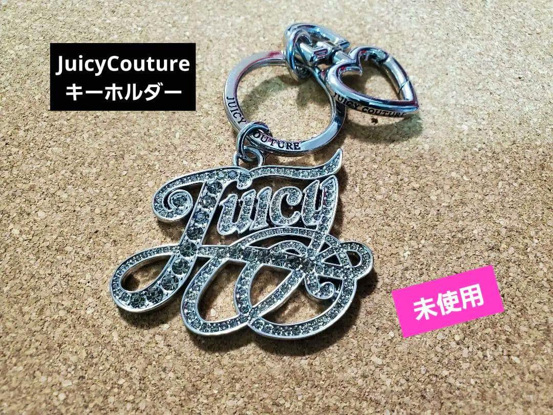Front view of a silver Juicy Couture rhinestone key holder bag charm with metal rings on a corkboard background.