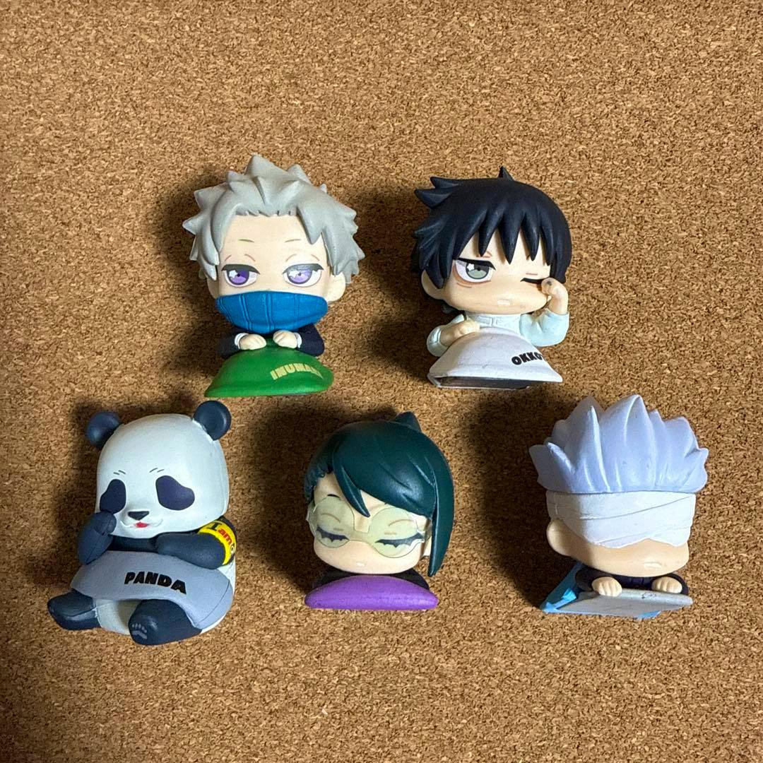Five small plastic Jujutsu Kaisen 0 “おねむたん” chibi figures arranged on a corkboard surface.