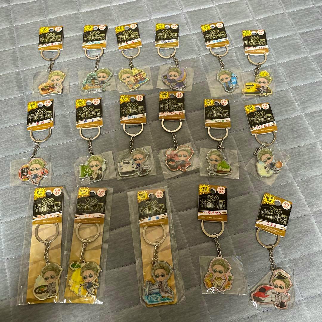 Seventeen Nanami Kento metal keychains (Jujutsu Kaisen) arranged on a grey quilted surface.