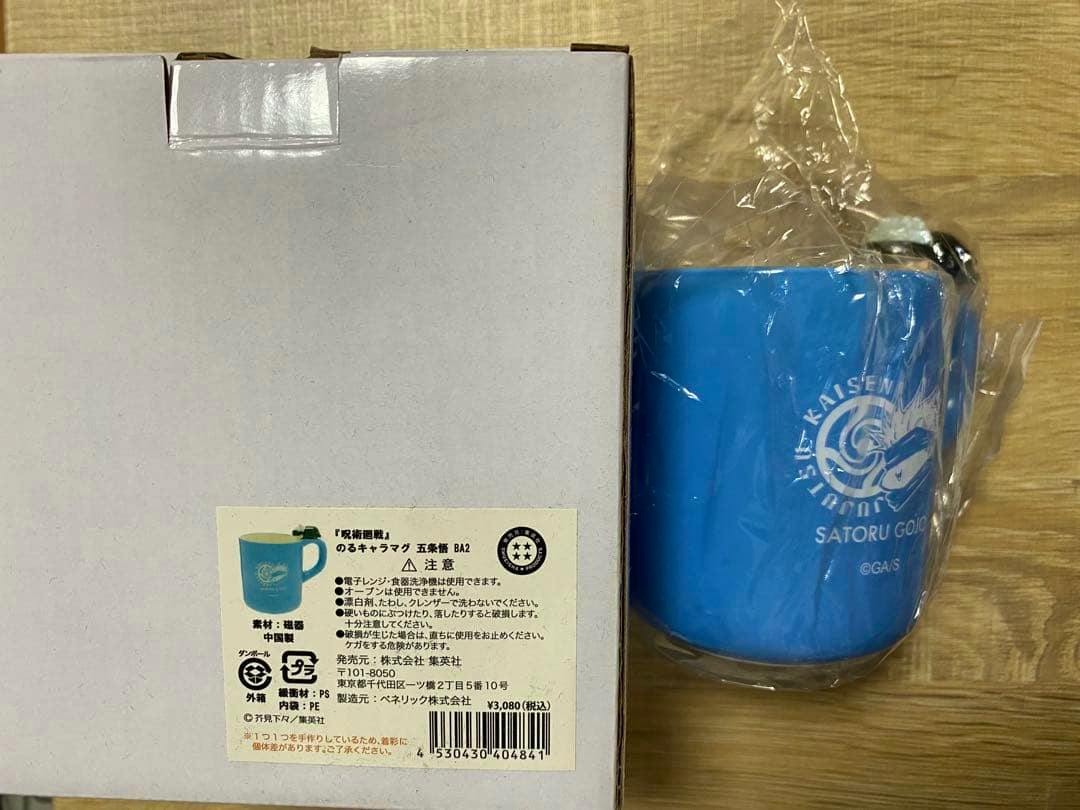 Blue Satoru Gojo character mug wrapped in plastic standing beside its white product box with a label.
