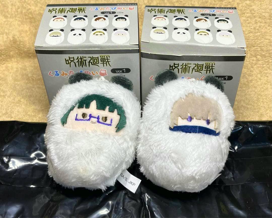 Two white fluffy round plush toys of Jujutsu Kaisen characters Zenin Maki (left) and Toge Inumaki (right) shown in front of two product boxes.