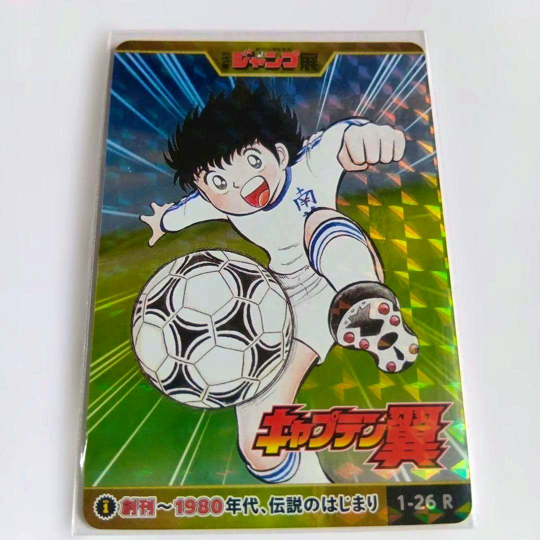 Front of the Captain Tsubasa photocard from the Jump 50th anniversary All-Star set, showing the character kicking a soccer ball on a holographic background with the card number 1-26R.