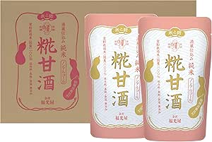 Two pink pouches of Junmai Koji Amazake standing in front of a brown box showing packaging with Japanese text.