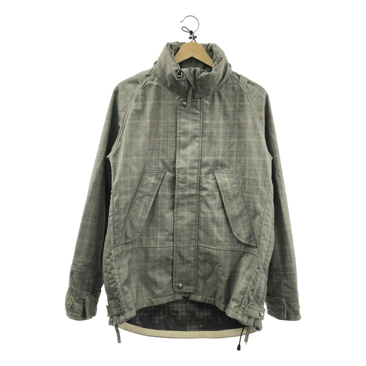 Gray JUNYA WATANABE COMME des GARCONS MAN men's hooded jacket hanging on a wooden hanger against a white background.