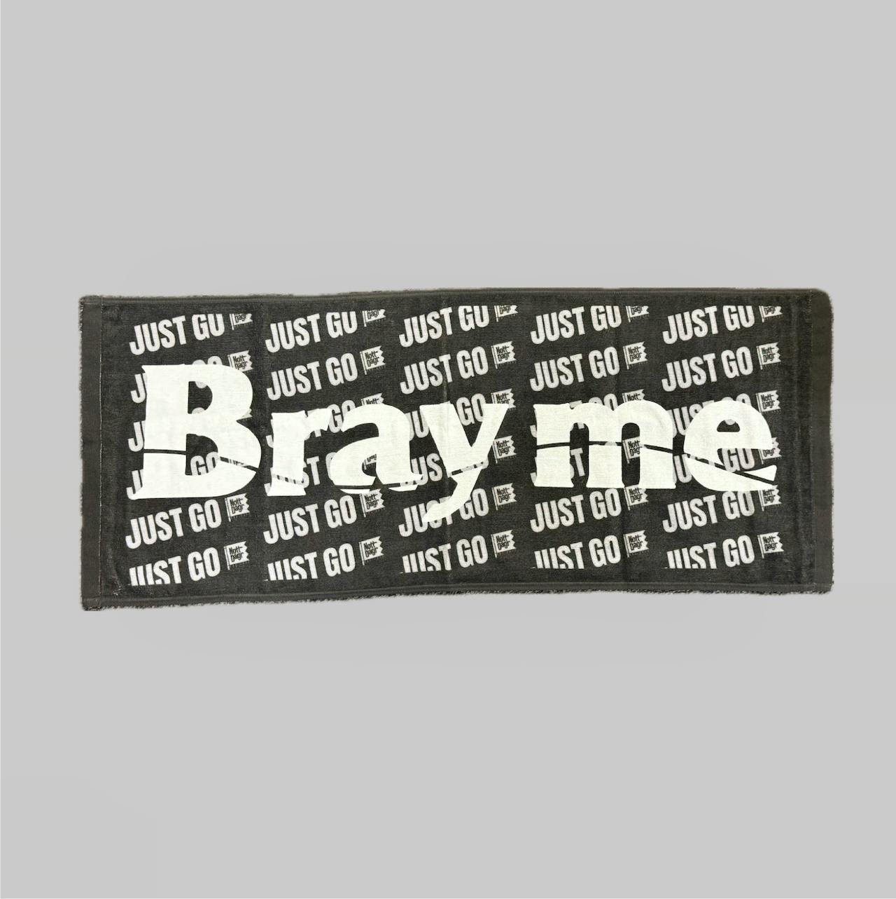 A black rectangular hand towel laid flat showing a repeating white "JUST GO" print and large white lettering across the center.
