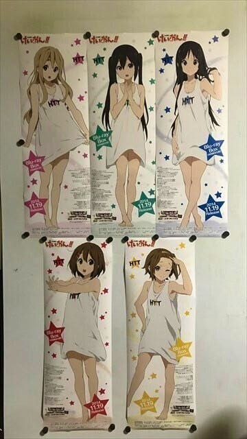 Five K-ON Blu-ray BOX promotional B2 half-size stick posters pinned to a wall, each showing an anime character wearing a short white dress.