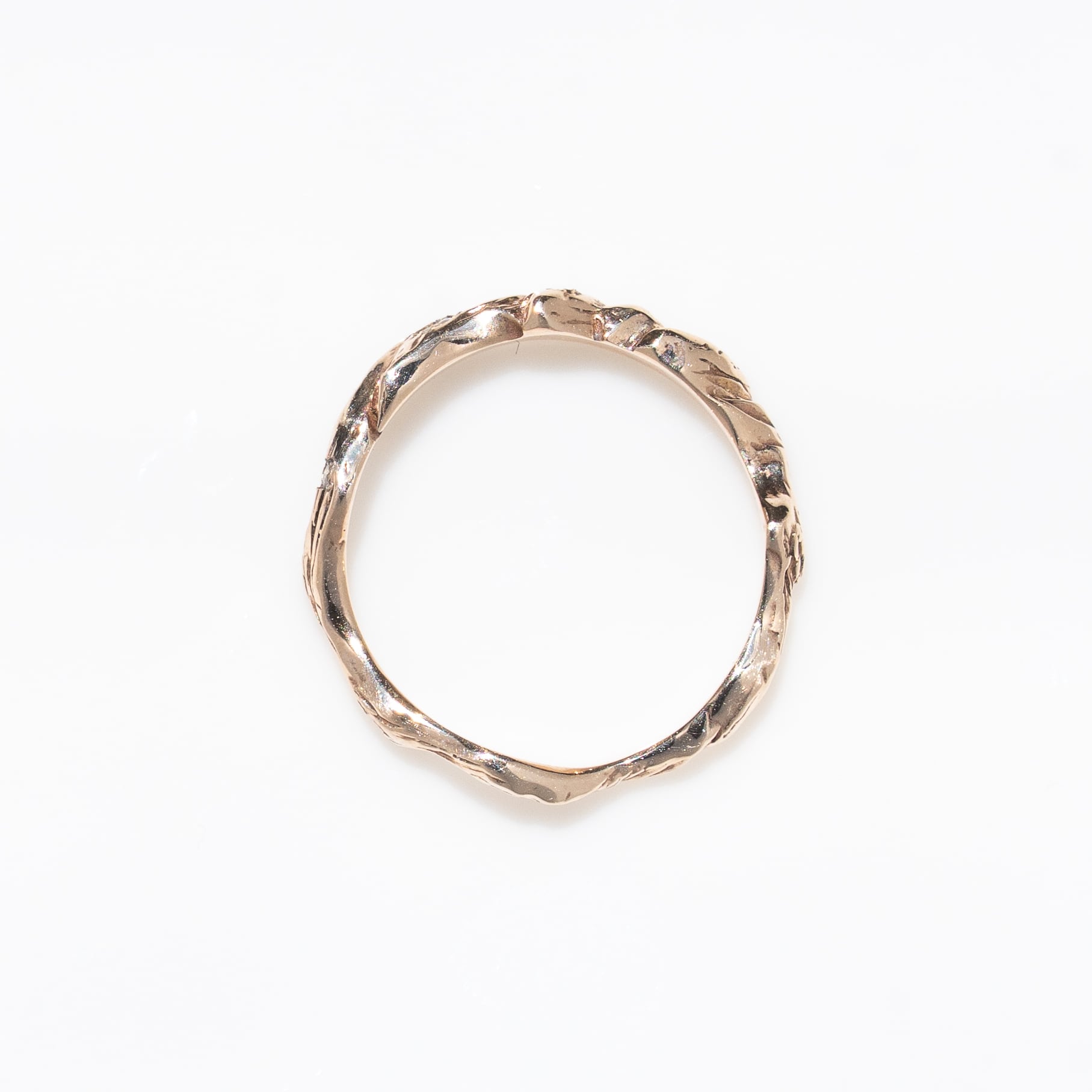Top-down photo of a K10 gold ring with a textured band on a white background.