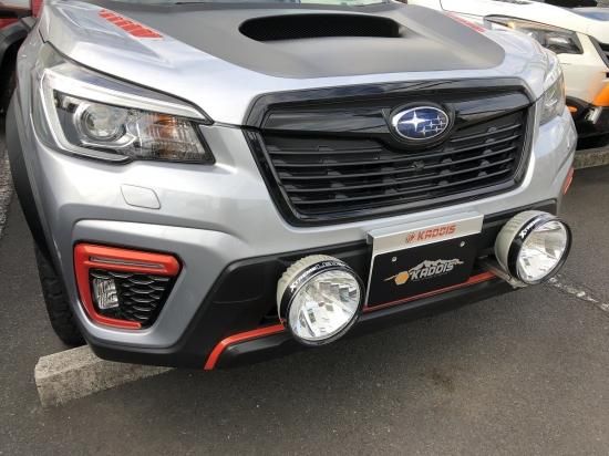 Front view of a Subaru Forester SK showing a KADDIS front lamp bracket with two round auxiliary lights mounted on the bumper.