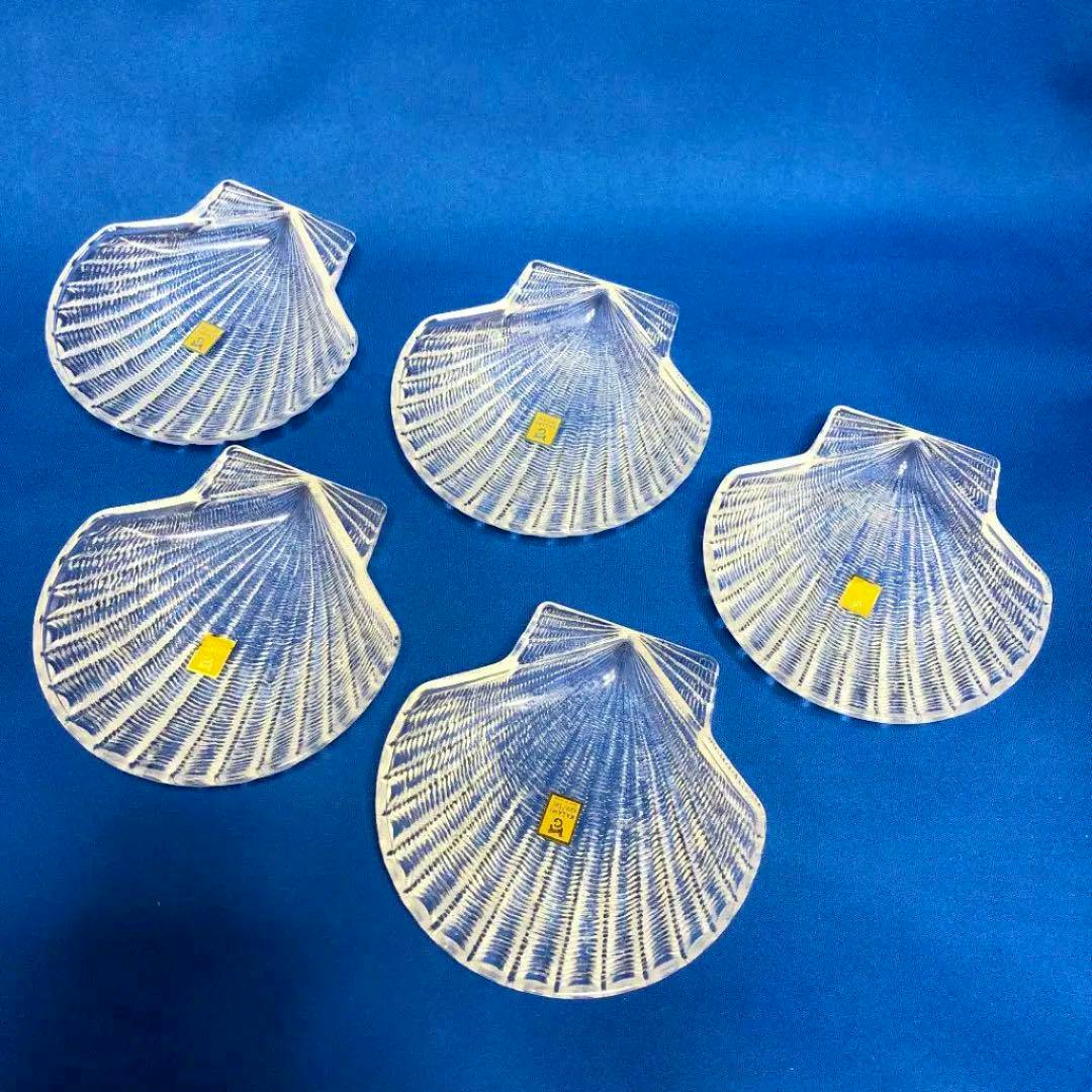 Five clear KAGAMI CRYSTAL scallop-shell glass plates arranged on a blue background.