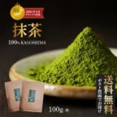 A bowl of bright green matcha powder with two small brown packets in front and Japanese text including “抹茶” and “100g”.