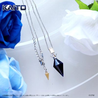 A sodalite stone pendant necklace with a small triangular charm on a chain, shown with blue and white flowers.
