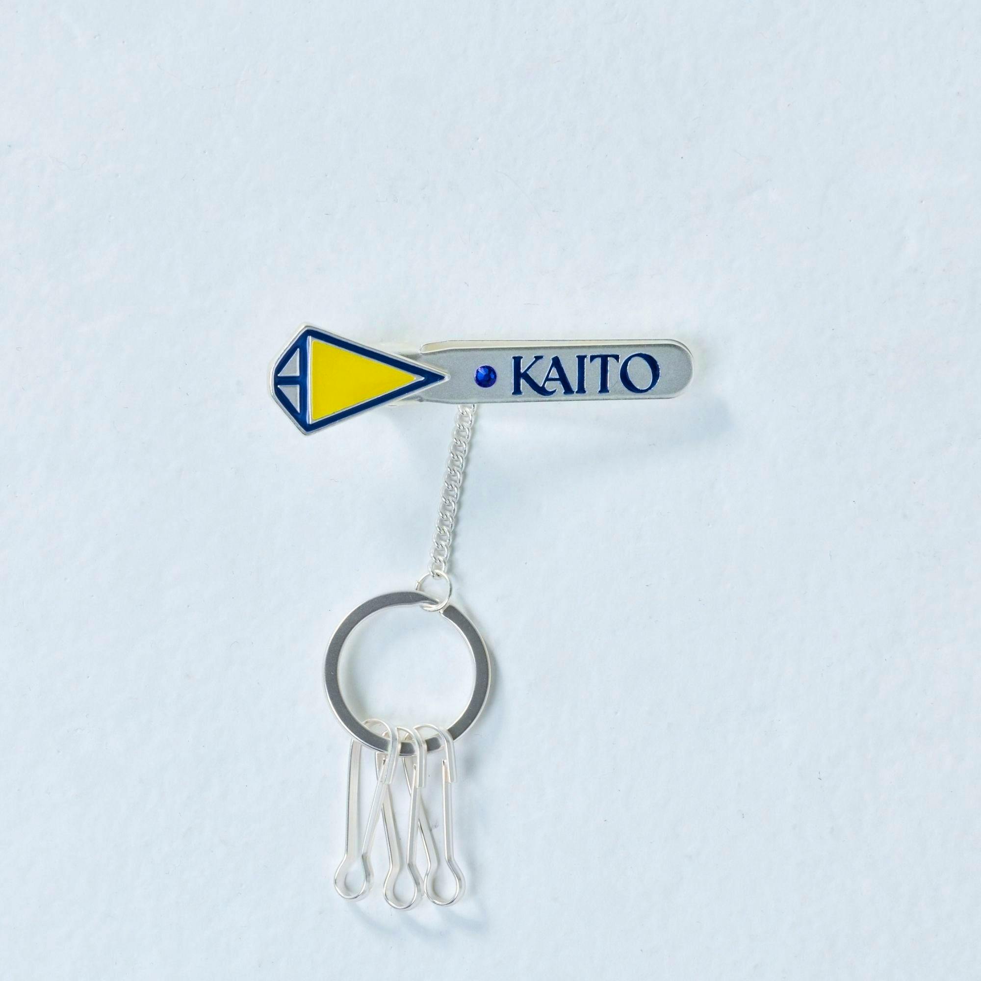 A KAITO metal keyring nameplate with blue "KAITO" lettering and a yellow‑blue triangular charm attached to a short chain and key ring.