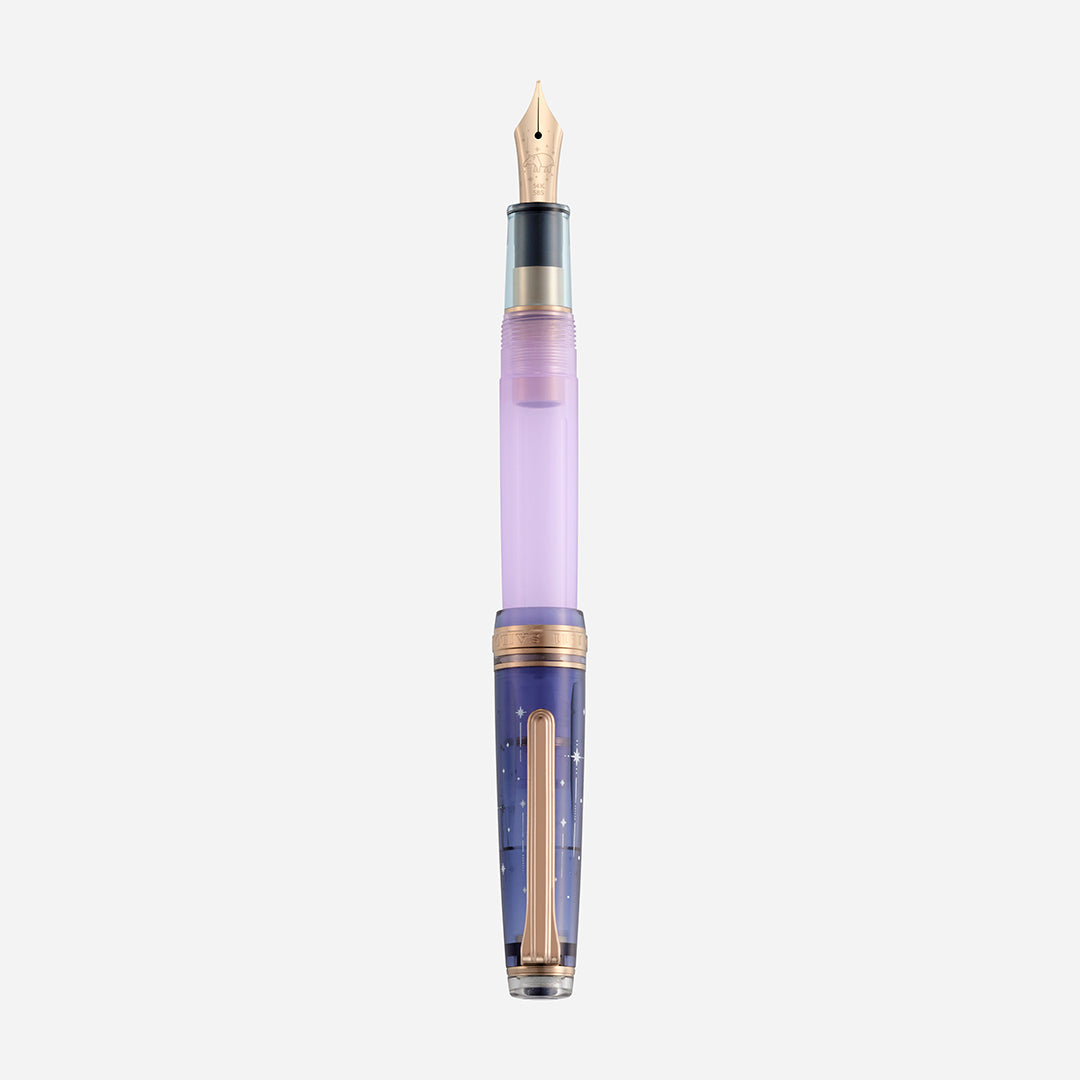 A fountain pen with a gold nib, translucent lavender grip section, and navy barrel decorated with small stars on a white background.
