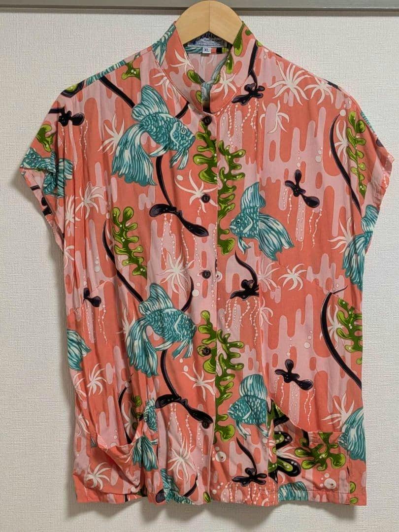 Front view of the KALAKAUA goldfish-pattern aloha shirt (XL) hanging on a wooden hanger against a wall.