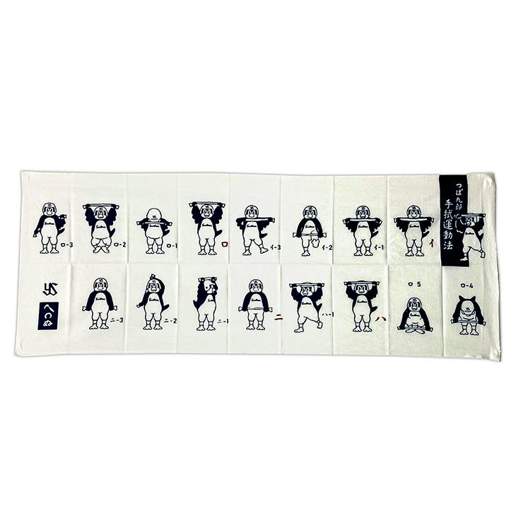 A white cotton hand towel showing rows of navy illustrations of つば九郎 (Tsubakuro) demonstrating towel-exercise poses.