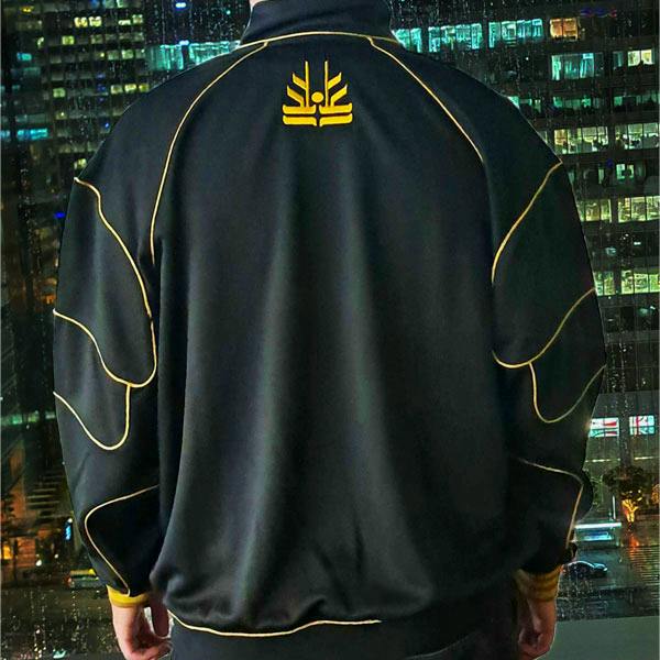 Back view of a black polyester Kamen Rider Kuuga Ultimate Form track jacket with yellow piping and emblem worn by a model.