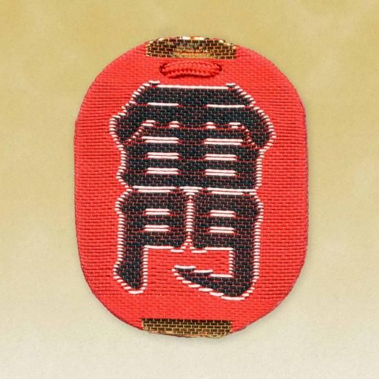 Front view of the red cloth amulet (雷門合格守) showing large black embroidered characters.