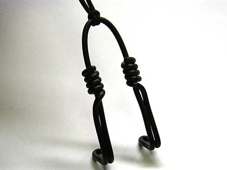 Black plastic nose hook (nose clip) hanging from a cord against a white background.