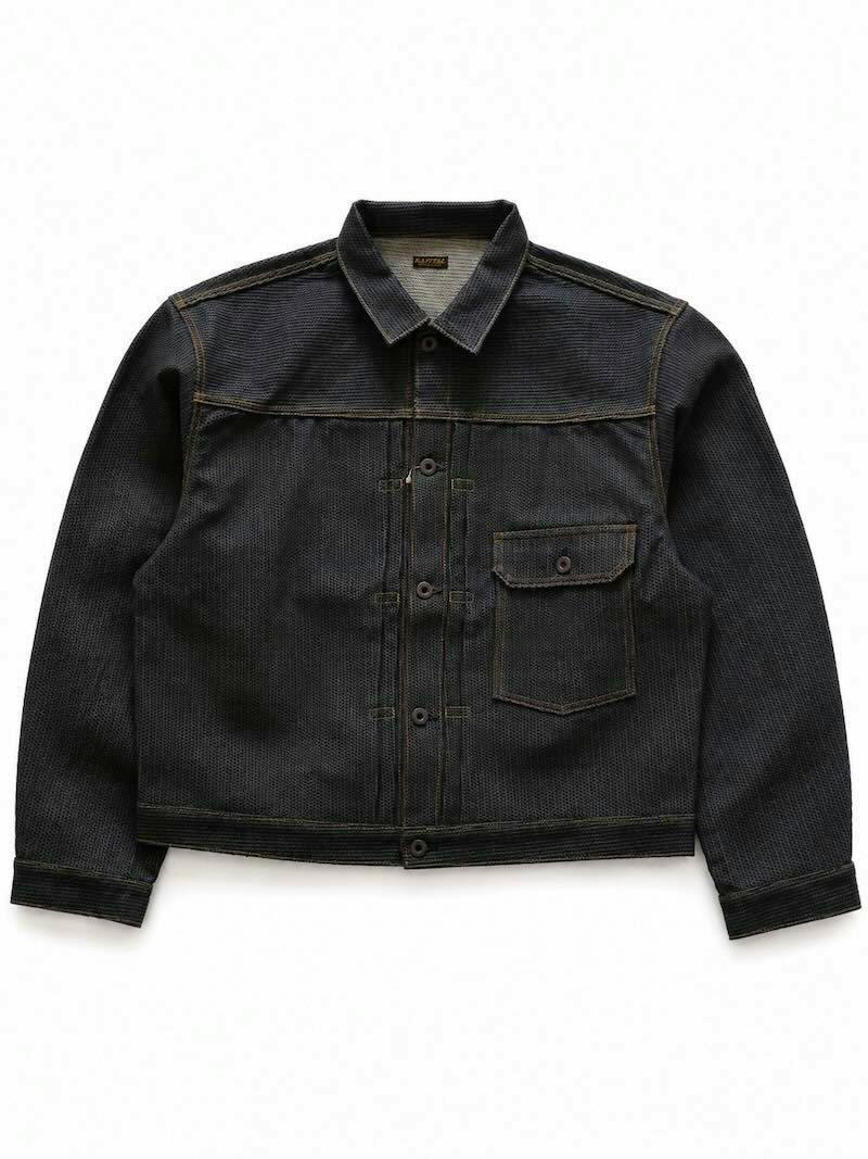 Front view of a dark textured denim men's jacket laid flat showing the collar, button-up front, and a single flap chest pocket.