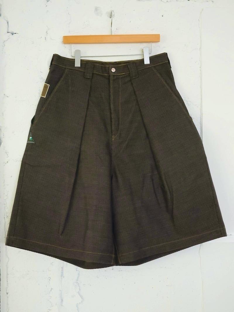 Front view of the men's cotton shorts hanging on a wooden hanger against a white wall.