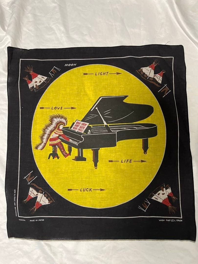 Black cotton bandana showing a yellow circular moon graphic with a grand piano and a figure wearing a feathered headdress at the center.