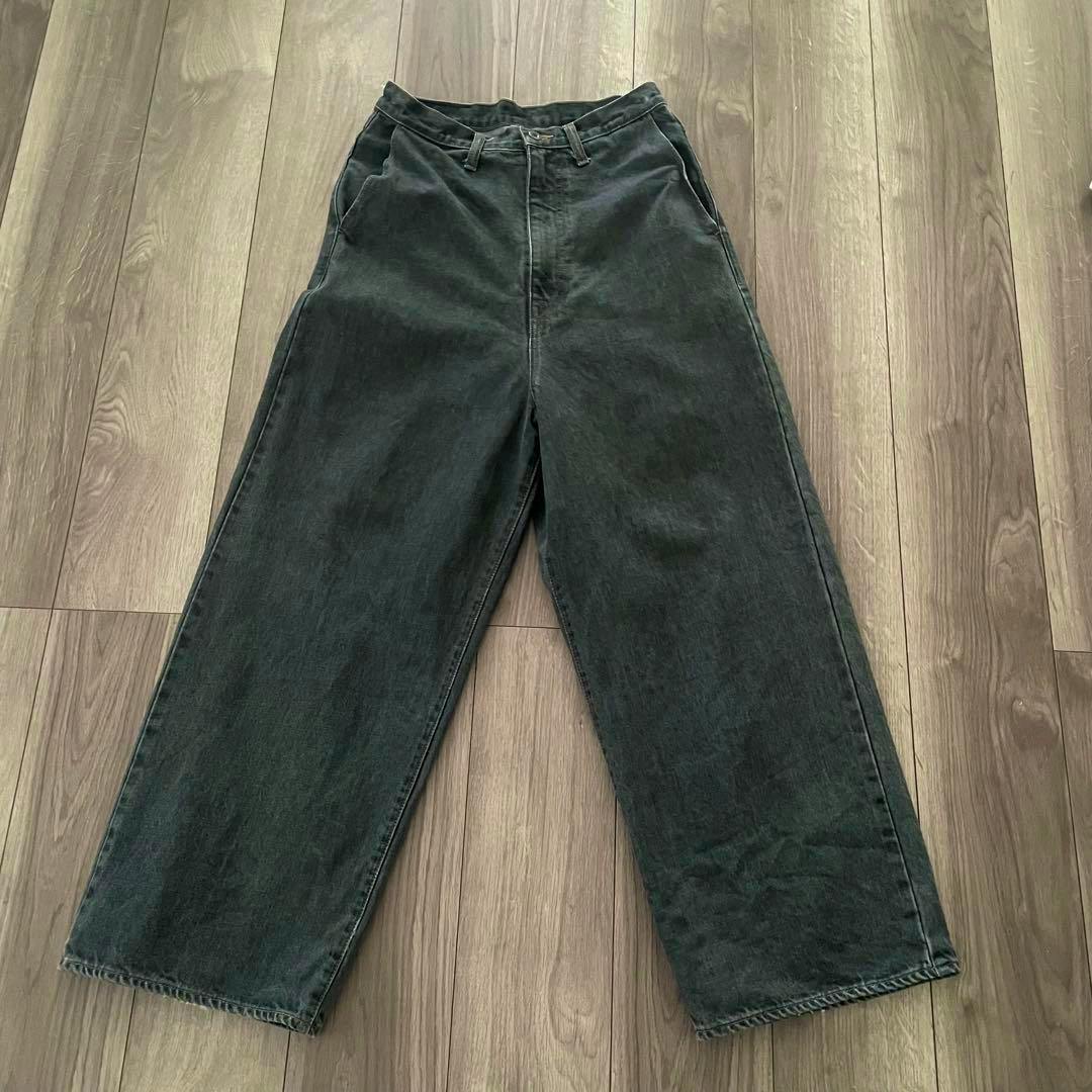 Flat-lay photo of KAPITAL black baggy denim pants laid out on a wooden floor.
