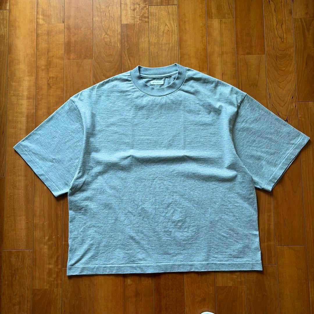 Light gray men's half-sleeve cotton shirt laid flat on a wooden floor.