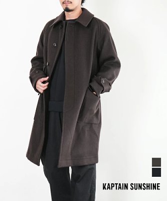 A man modeling the men's wool traveller coat by KAPTAIN SUNSHINE against a white background.