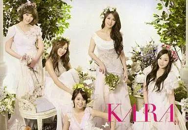 Photocard showing five women in white dresses seated and standing among flowers with pink "KARA" text at the bottom right.
