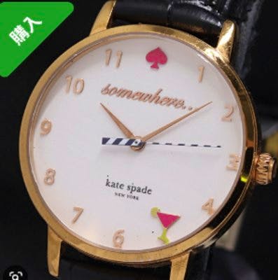 Front view of the Kate Spade men's wristwatch showing a white dial with "somewhere..." text, gold-tone case, black leather strap, and a small martini-glass motif.