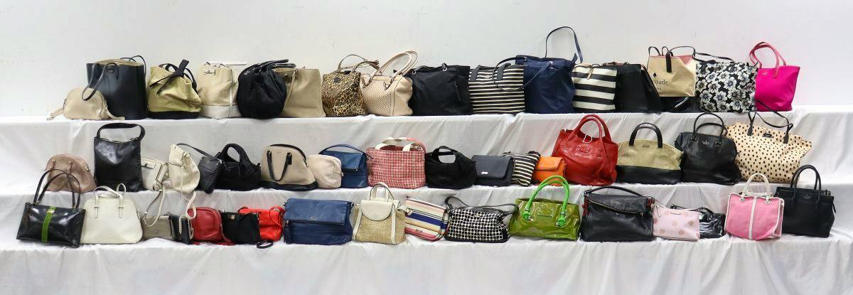 Rows of assorted kate spade New York handbags and totes displayed on white draped shelves.