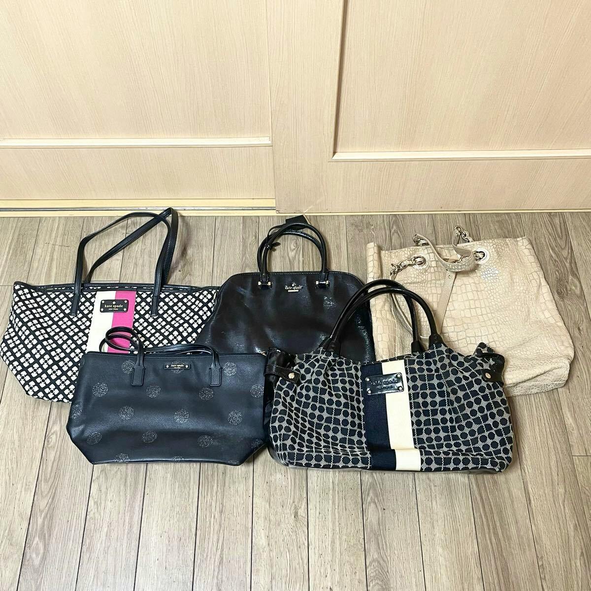 Five kate spade new york bags arranged on a wooden floor, showing varied styles and colors.