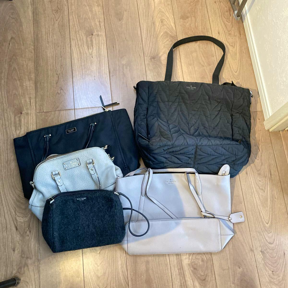 Five Kate Spade bags of various styles arranged on a wooden floor.