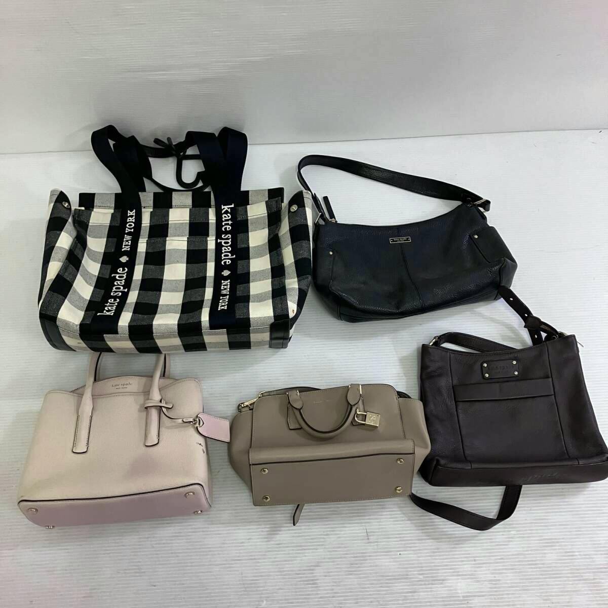 Five bags arranged on a white surface, including a black-and-white check kate spade tote and four handbags in various colors.