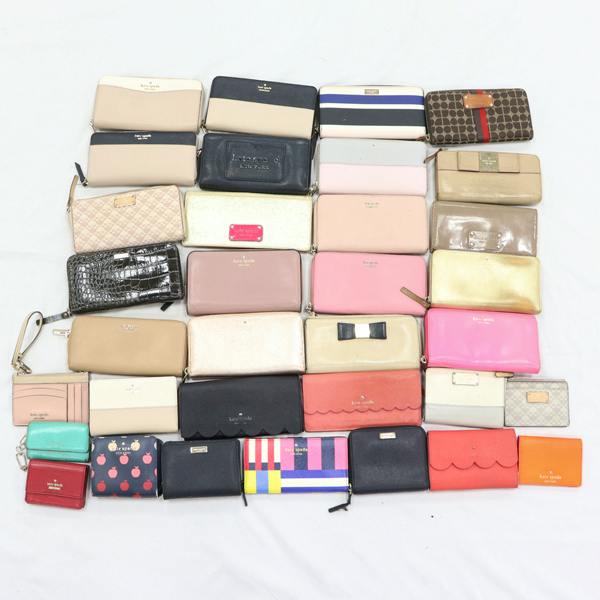 Top-down photo of 34 Kate Spade wallets and small accessories arranged on a white background.