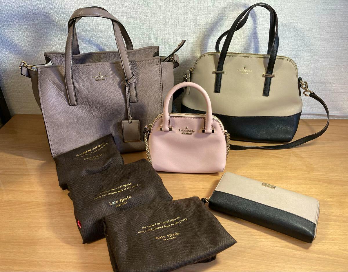 Three kate spade handbags, a two-tone wallet, and several kate spade dust bags displayed on a wooden surface.