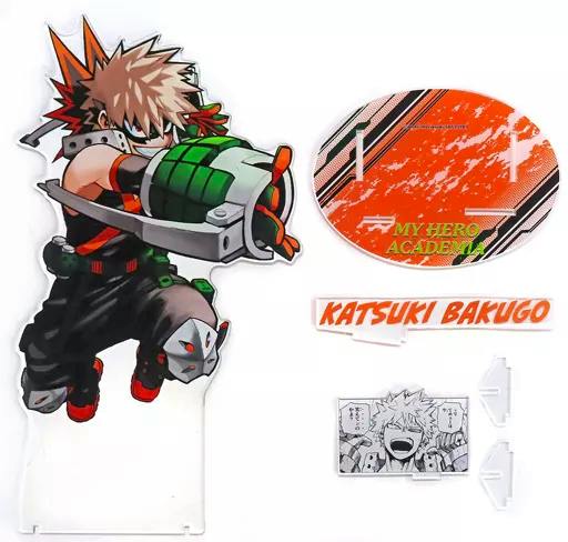 Acrylic stand set showing an acrylic figure of Katsuki Bakugo with an oval base, nameplate, and a small comic-panel insert.
