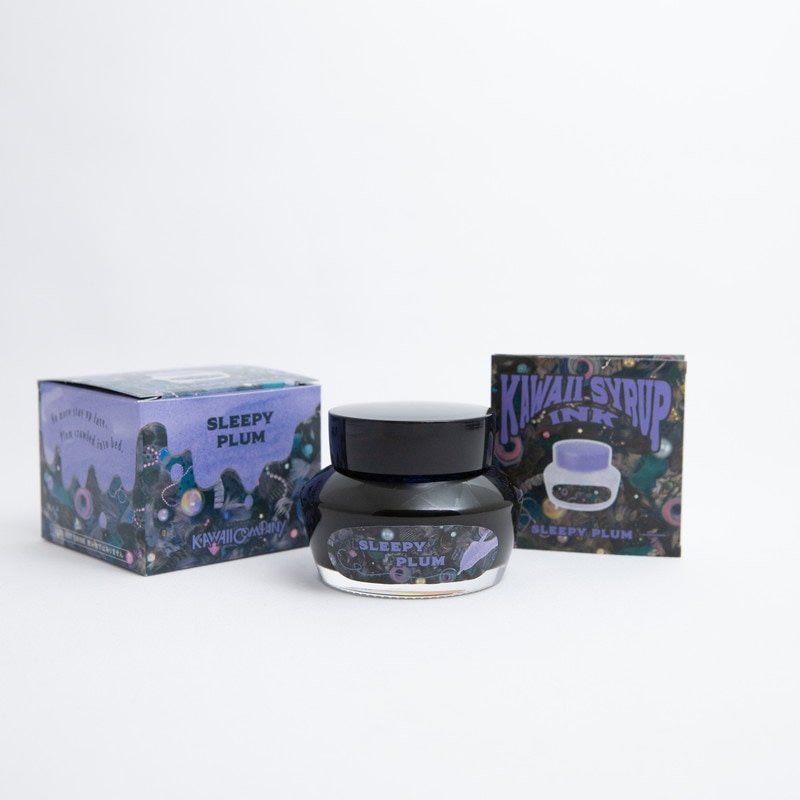 Glass bottle of SLEEPY PLUM fountain pen ink centered between two matching decorative boxes.